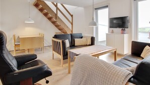Ein modernes Wohnzimmer mit einer Couch, einem Sessel, einem Couchtisch und einem Fernseher.