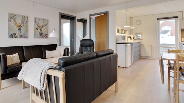 Ein modernes Wohnzimmer mit einer Couch, einem Esstisch und einer Küchenzeile.