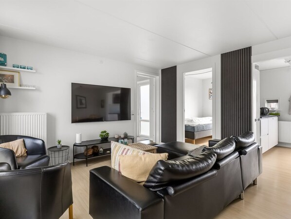 A modern living room with a black leather sofa, a TV, and a small side table.