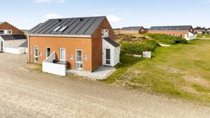 Una hilera de casas modernas de un piso, de ladrillo, con techos planos y grandes ventanales, ubicada en un área verde y ordenada.