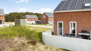 Zona residencial con casas de ladrillo, una zona de barbacoa y un cobertizo verde.