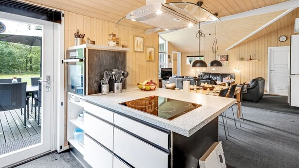 A modern kitchen with a central island, built-in appliances, and a dining area with a black leather couch.