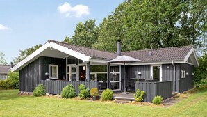 A modern two-story house with a covered patio and a large chimney.