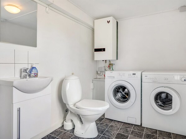 A modern bathroom with a toilet, sink, and two washing machines.