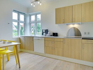 Een koelkast, een oven, een vaatwasser, kookgerei, borden en bestek