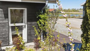 Une maison avec un toit recouvert de tuiles rouges, une façade en bois et une fenêtre dotée d’un cadre blanc.