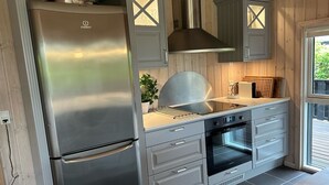 Une cuisine moderne équipée d’un réfrigérateur en acier inoxydable, d’un four et d’une plaque de cuisson intégrée.