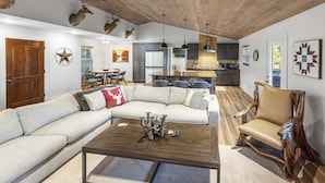 Uma sala de estar ampla com um sofá modular, uma mesa de centro de madeira e uma cadeira de balanço de madeira com design exclusivo.