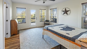 Quarto com cama, ventilador de teto, decoração de estrelas e vista pela janela.