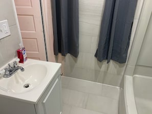 Une salle de bain avec un lavabo blanc, un miroir, une porte et un espace douche.