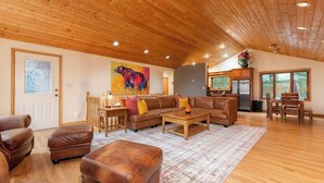 Un ampio soggiorno con soffitto in legno, un grande quadro, una sala da conversazione e un'area pranzo con tavolo e sedie.