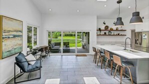 Une cuisine moderne dotée d’un grand îlot central, de fenêtres de toit et offrant une vue sur l’extérieur.
