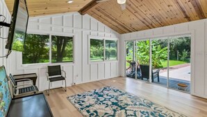 Une pièce spacieuse avec de grandes fenêtres, un ventilateur de plafond et un tapis à motifs.
