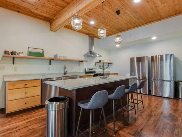 Una cocina moderna con vigas de madera, electrodomésticos de acero inoxidable y taburetes de bar.
