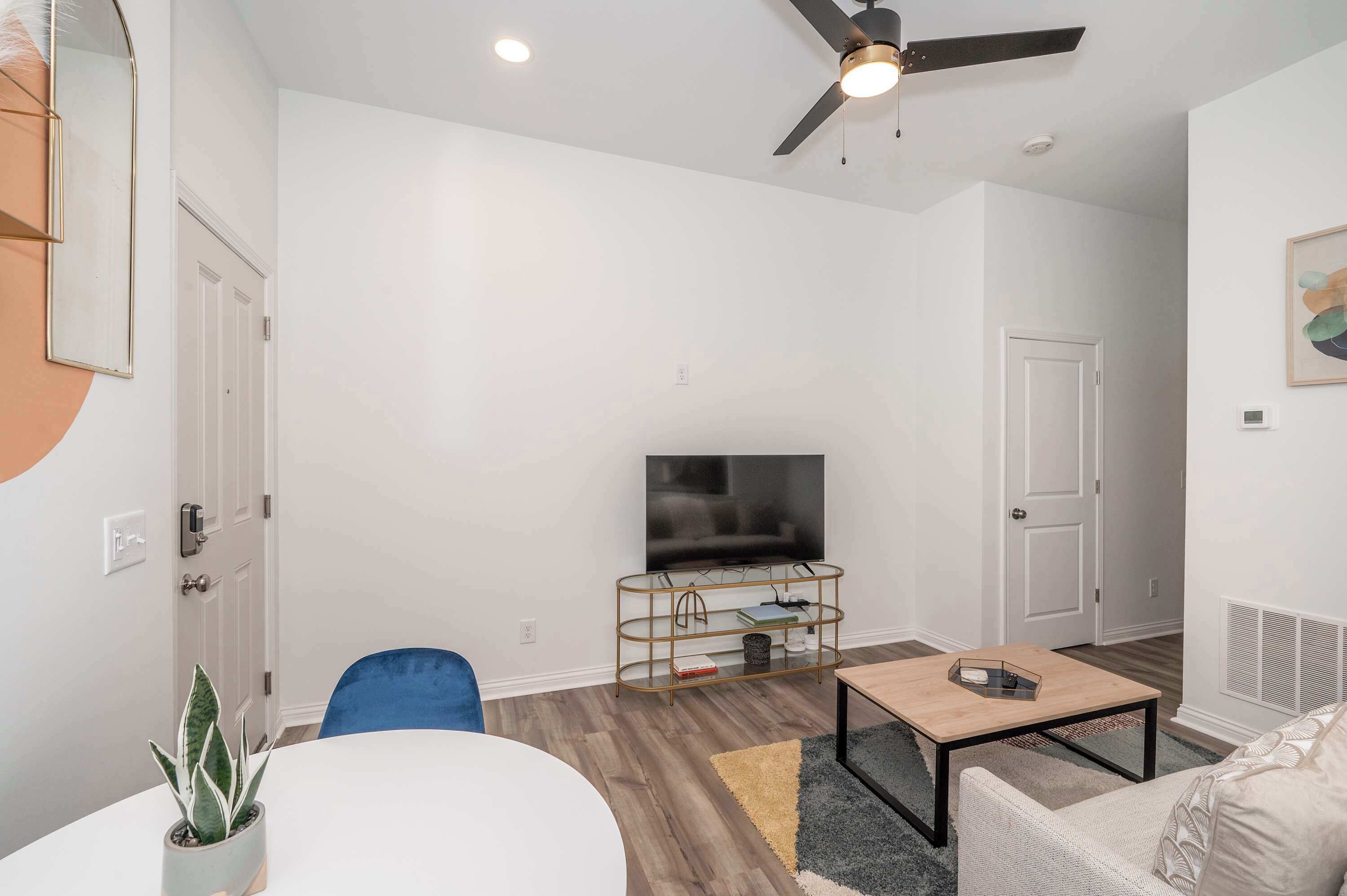 A modern living room with a flat-screen TV, a ceiling fan, and a coffee table.