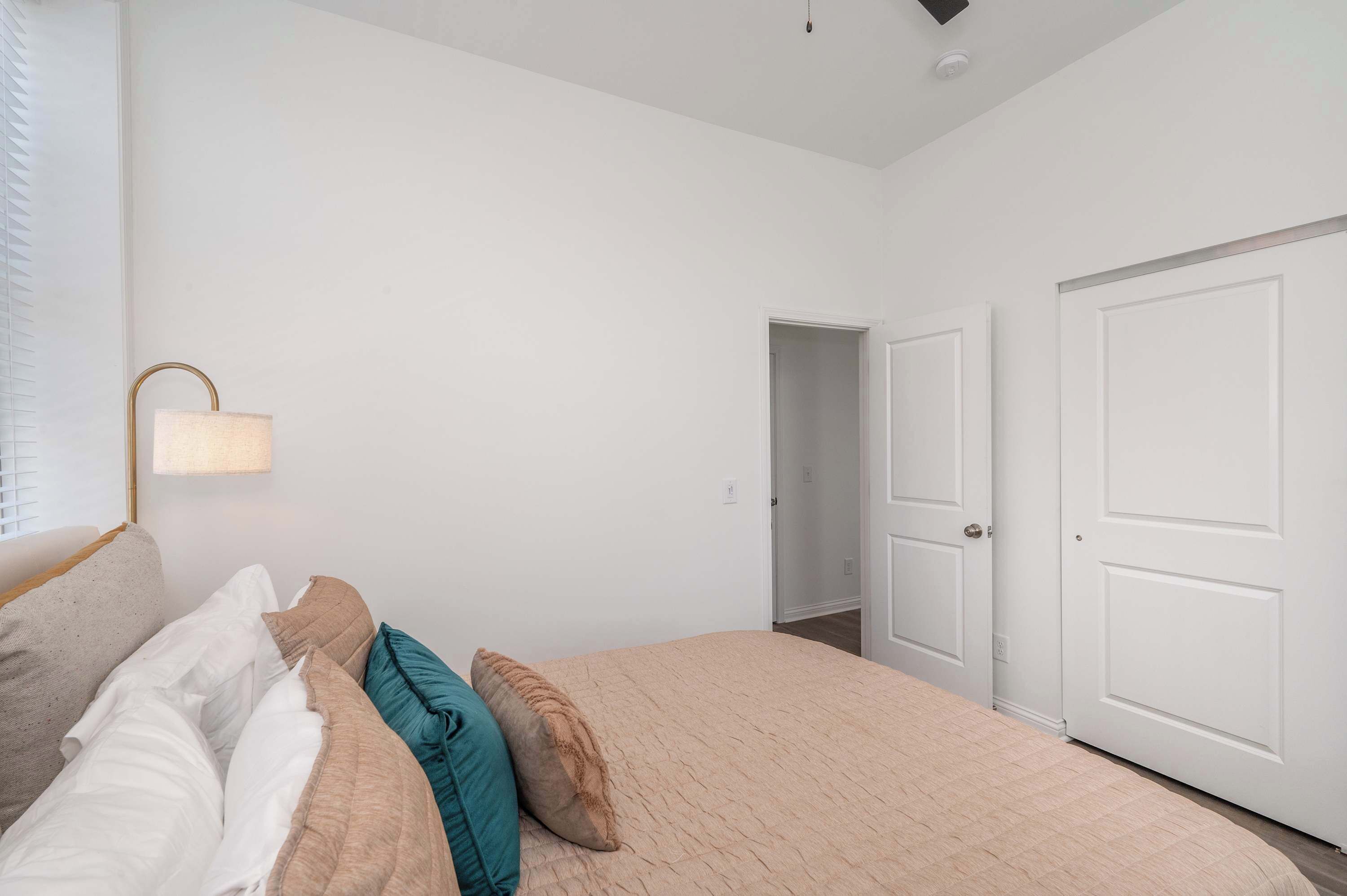 A bedroom with a bed, a nightstand, a lamp, and a door to a closet.