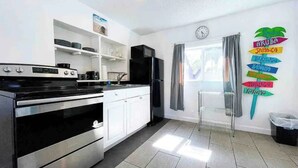 A modern kitchen with white cabinets, a black stove, and a refrigerator. There is a window with curtains and a wall clock. - Private Parking + Own Patio
+ FREE Bikes 1b/1b Apt (Hollywood)