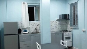 A compact kitchen with a refrigerator, stove, microwave, and sink.