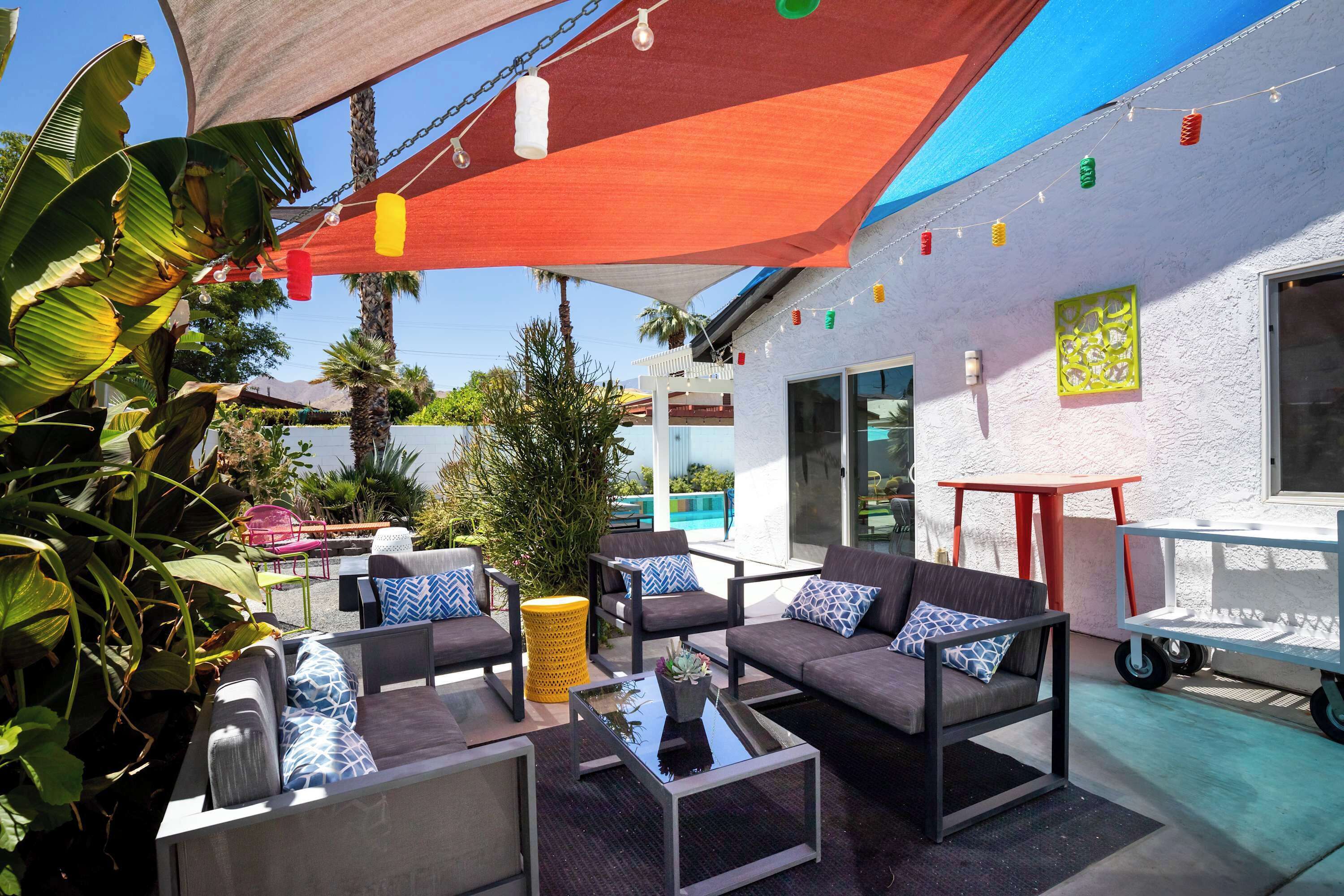 Un espace extérieur aménagé avec des meubles modernes, une piscine et un bâtiment blanc doté d’un balcon.