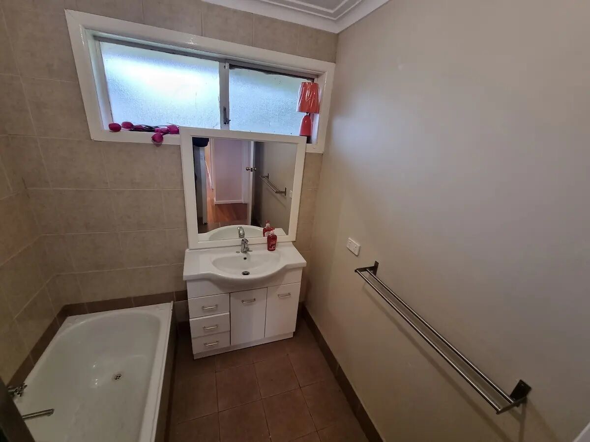 Une salle de bain avec une baignoire, un lavabo avec un miroir et une fenêtre au-dessus du lavabo.