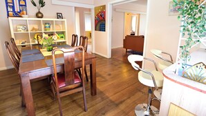 Un comedor con una mesa y sillas de madera, un armario blanco con estantes, y un cuadro en la pared.