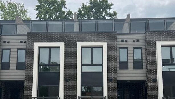 A modern building with three-story brick and glass structures, featuring large windows and a parking lot in front. - Minutes To The Falls:  Stylish Townhome Gem! (Niagara Falls)
