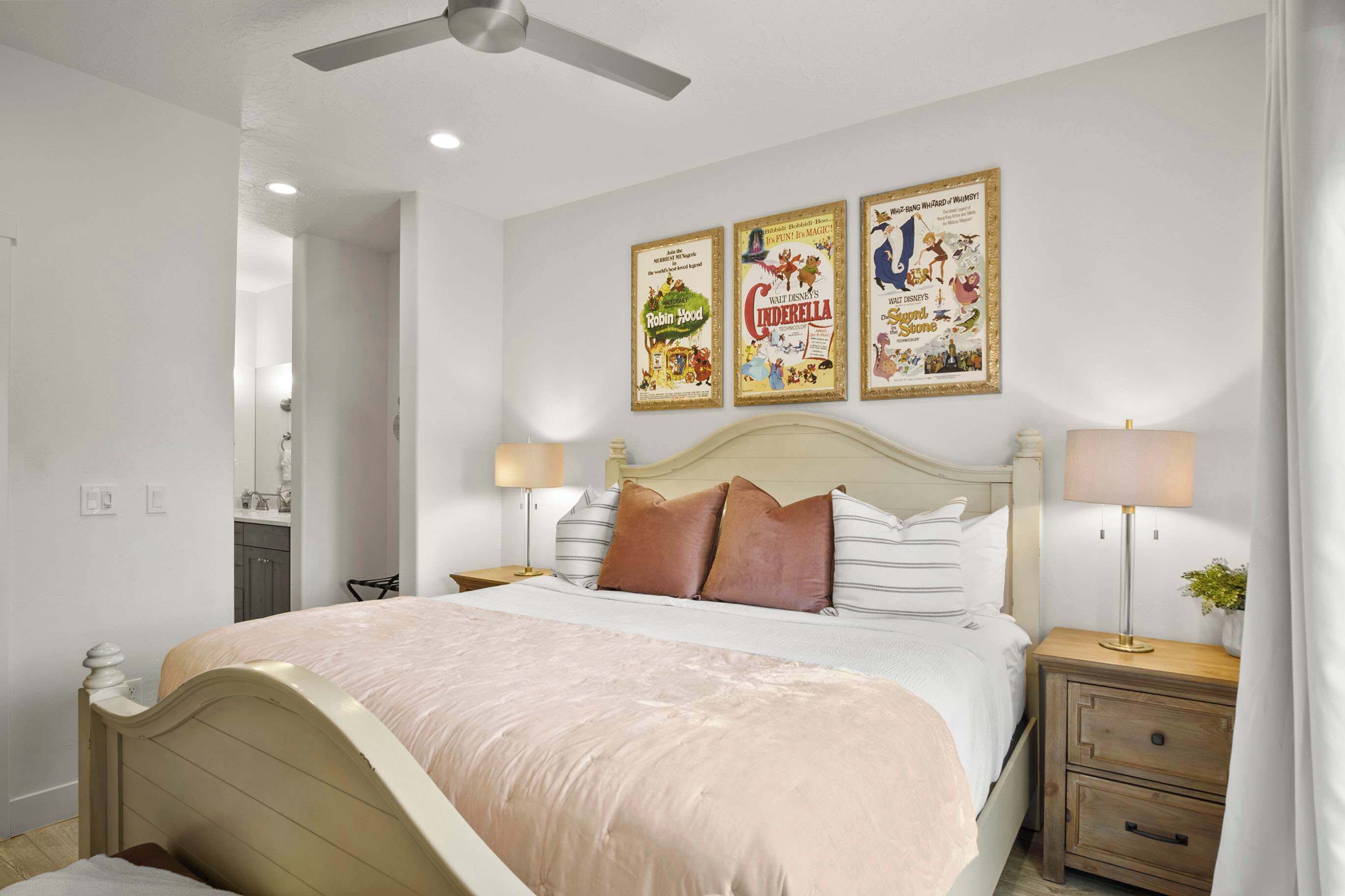 A bedroom with a bed, nightstands, a ceiling fan, and three posters on the wall.