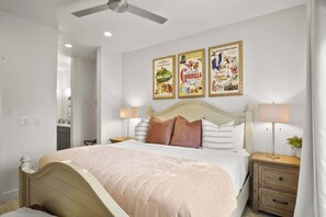 A bedroom with a bed, nightstands, a ceiling fan, and three posters on the wall.