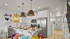A modern kitchen with white cabinets, stainless steel appliances, and colorful stools. - Live in Fantasy at Disney in the Desert! (Washington)