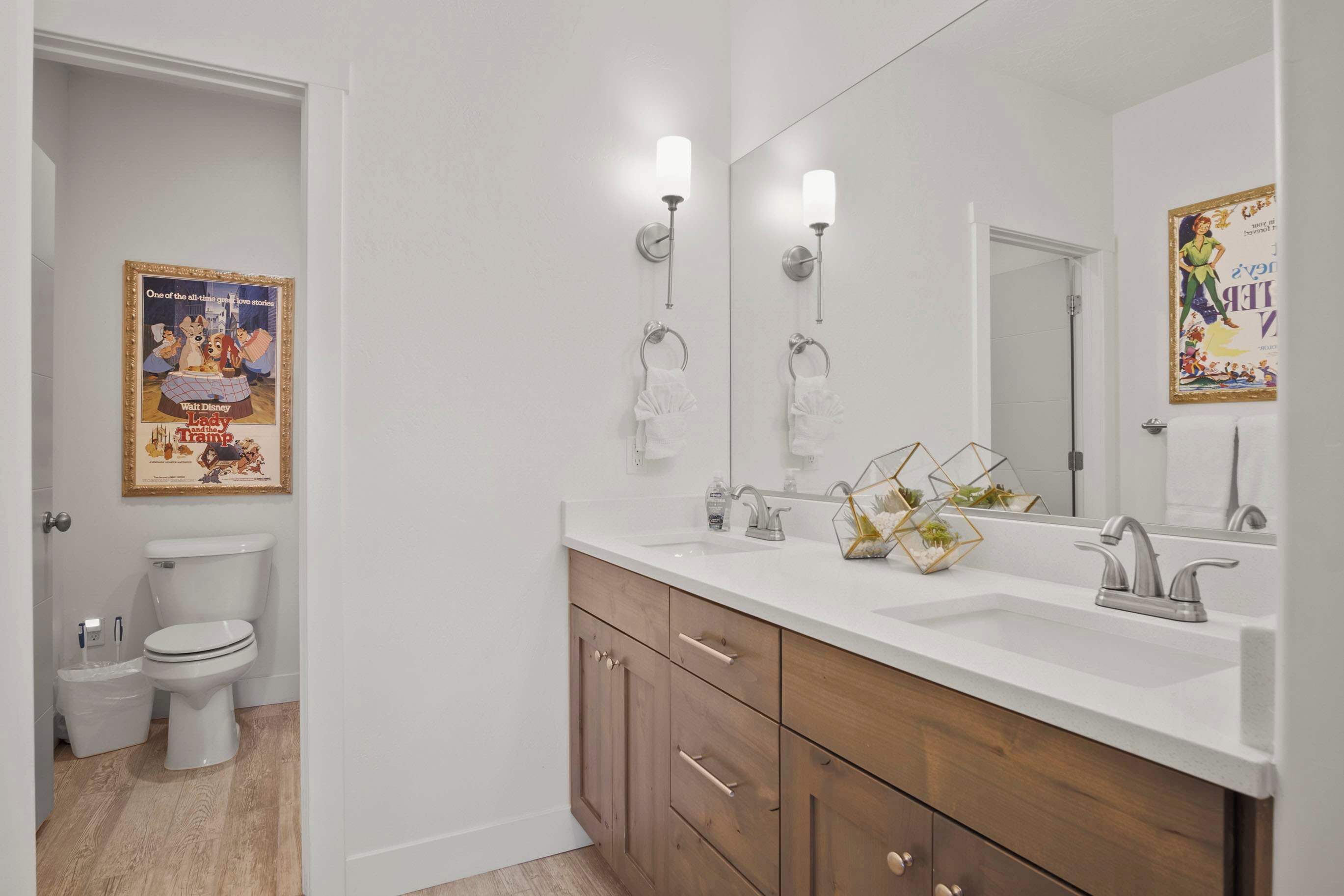 A bathroom with a white toilet, a sink with a mirror, and wooden cabinets.
