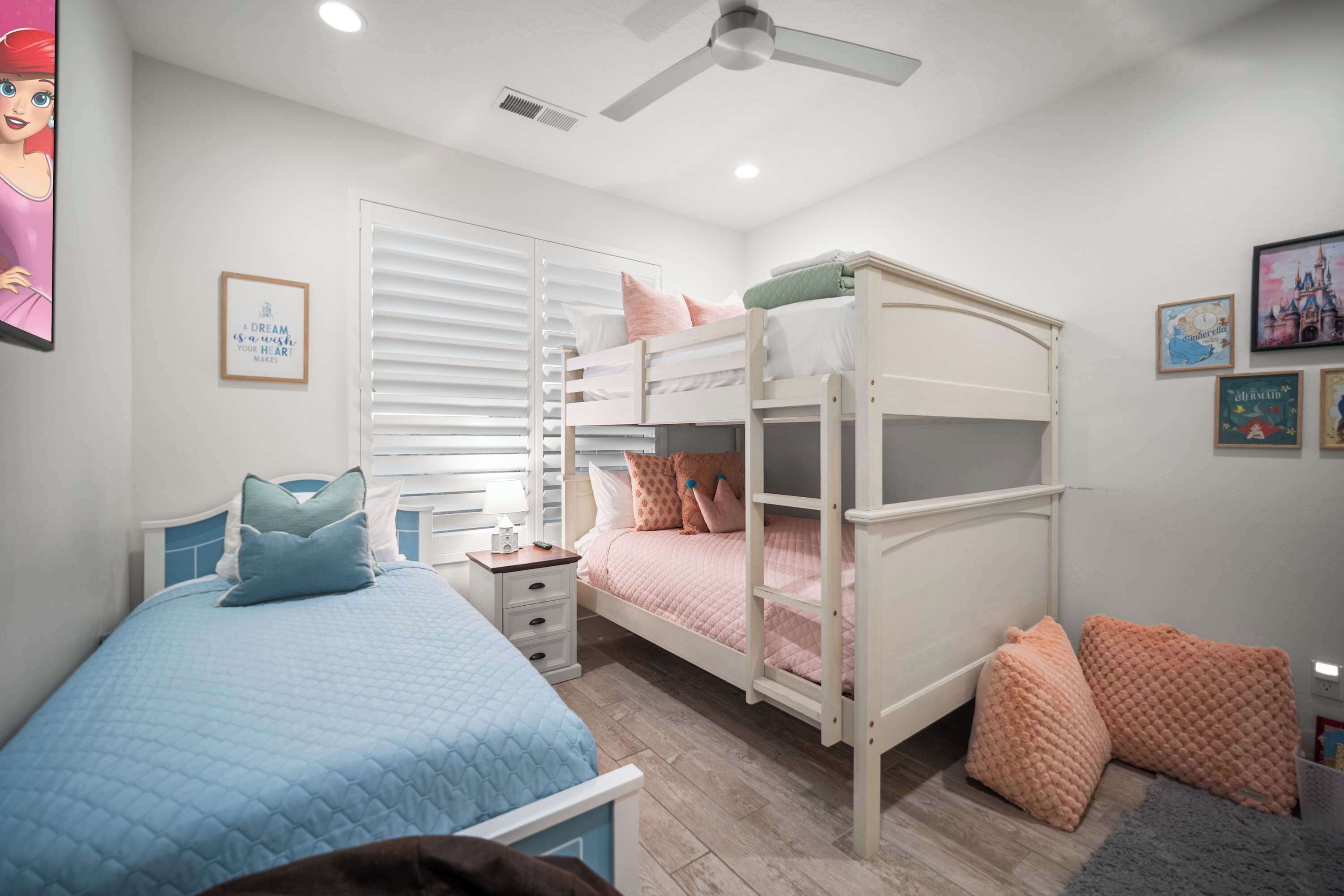 A bedroom with a bunk bed, a single bed, a nightstand, and a ceiling fan.