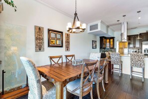 A dining area with a wooden table and chairs, a chandelier, and artwork on the walls.
