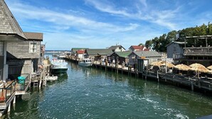 A waterfront area with wooden buildings, a dock, and a boat.