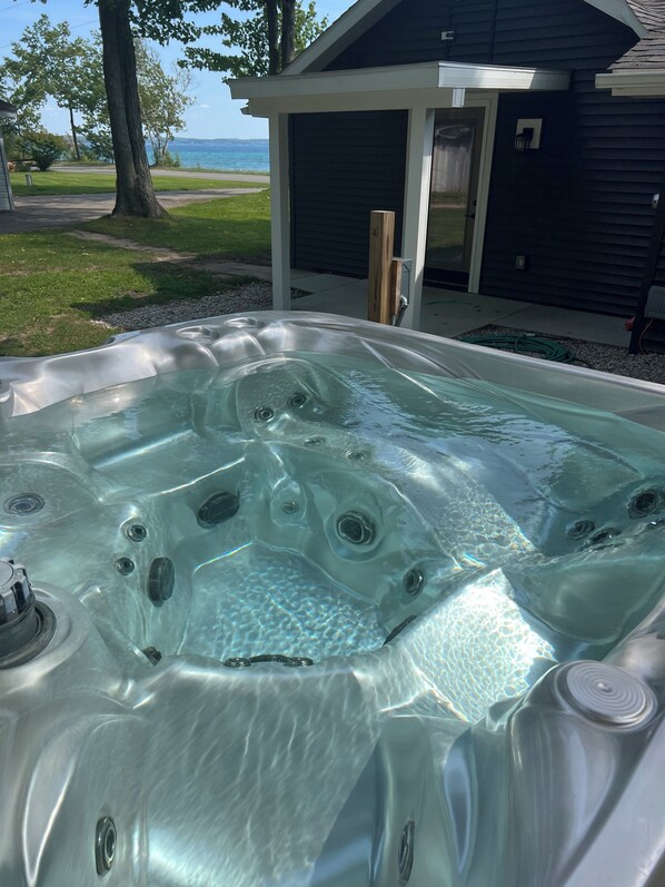 A hot tub with a clear view of the surrounding area, including a house and a grassy lawn.