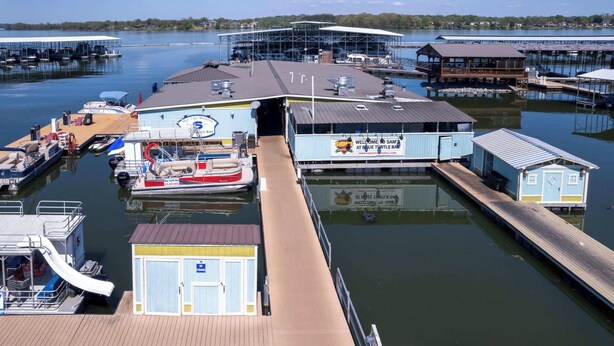 Un port de plaisance avec des bateaux amarrés, une rampe d’accès aux bateaux abritée et un petit bâtiment sur lequel est affichée une enseigne accueillant les visiteurs à Sam’s, dans la baie de Blue Turtle.