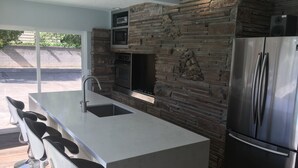 Una cocina moderna con una isla central, electrodomésticos de acero inoxidable y una pared de acento de piedra.