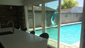 Una cocina moderna con una isla grande y una puerta corrediza de vidrio que da a una zona de piscina.