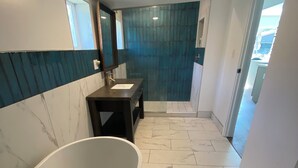 Un baño moderno con una bañera independiente, un tocador con espejo y una zona de ducha con puerta de vidrio.