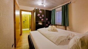 Ein Hotelzimmer mit Bett, Duschbereich und einem Schrank mit floralen Verzierungen.