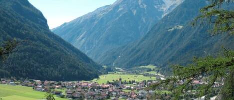 A valley with a small town nestled between mountains, a river, and green fields.