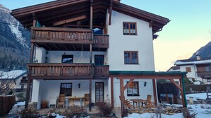 A multi-story chalet with wooden balconies, a covered patio with outdoor seating, and a mountainous backdrop. - Rätia I by Interhome (Pfunds-Samnaun)