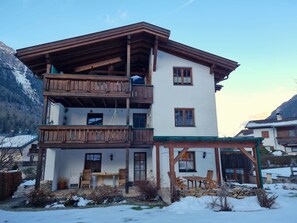 A multi-story chalet with wooden balconies, a covered patio with outdoor seating, and a mountainous backdrop. - Rätia I by Interhome (Pfunds-Samnaun)