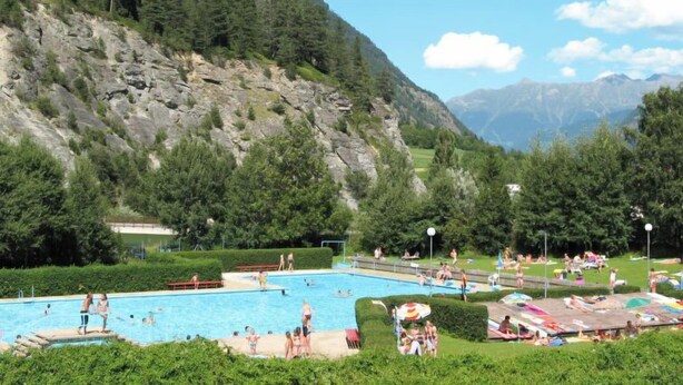 A swimming pool surrounded by lush greenery and mountains in the background. - Rätia I by Interhome (Pfunds-Samnaun)