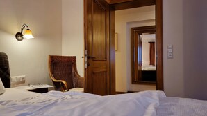 A hotel room with a bed, a chair, a lamp, and a door leading to another room. - Rätia I by Interhome (Pfunds-Samnaun)