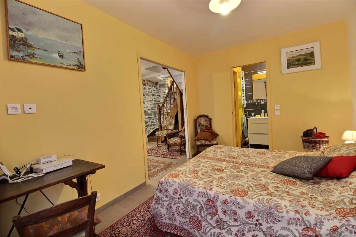 A bedroom with a bed, a desk, a chair, and a painting on the wall.