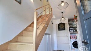 Eine Holztreppe führt zu einem Raum mit einer Waschmaschine und einer Tür, über der sich ein Schild befindet.