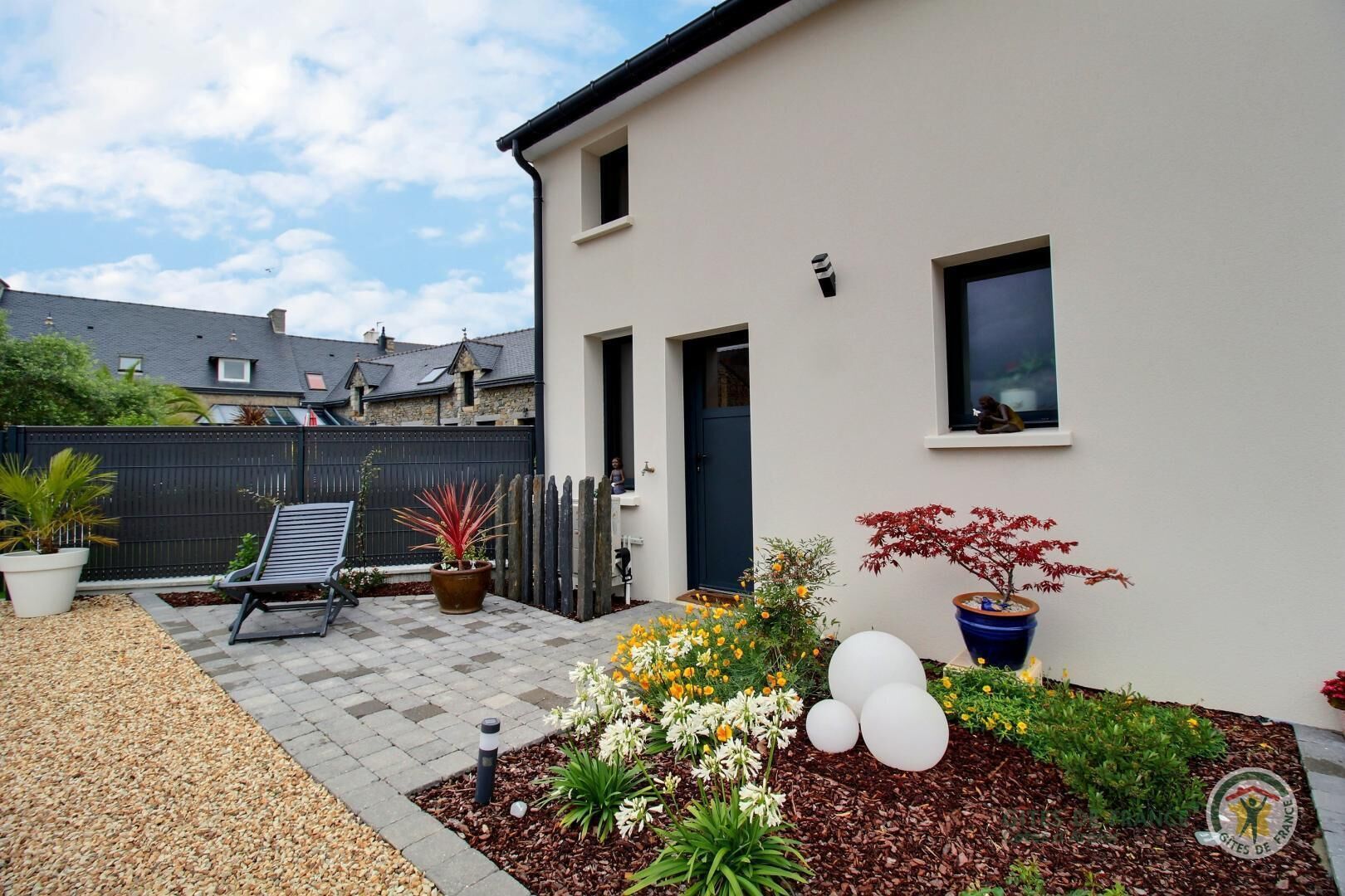 A residential backyard with a patio, potted plants, and a small garden area.