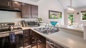 Una cocina moderna con armarios de madera oscura, electrodomésticos de acero inoxidable y un amplio ventanal que proporciona luz natural.