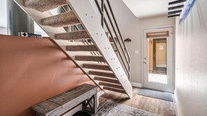 Una escalera moderna con un diseño único, un banco y una puerta que da a un espacio exterior.