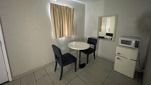 A small, clean room with a round table, two chairs, a microwave, and a mirror on the wall. - Black Horse Motel (Apple Valley)